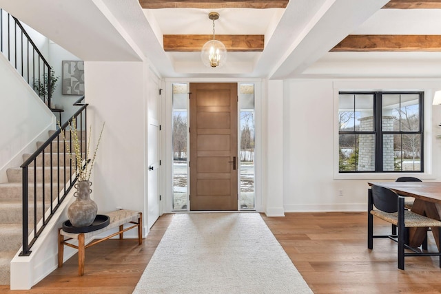 entryway featuring wood finished floors, stairs, baseboards, and beamed ceiling