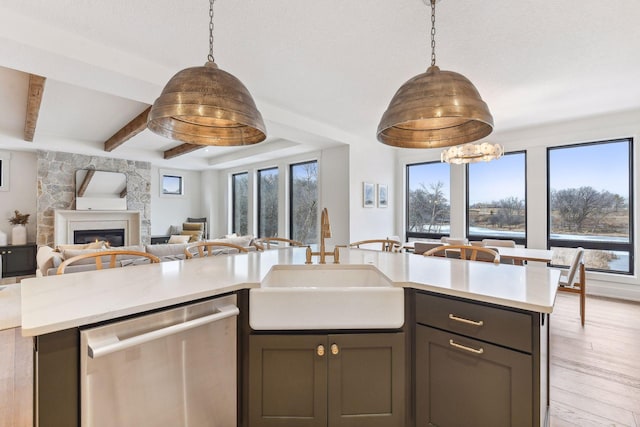 kitchen with dishwasher, a sink, open floor plan, light wood-style floors, and light countertops