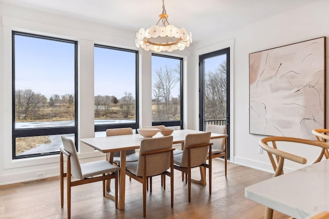 dining space featuring a chandelier, plenty of natural light, light wood-style flooring, and baseboards