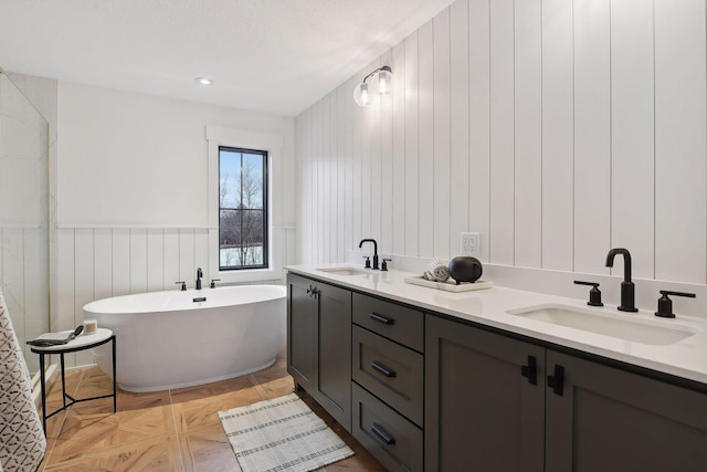 full bath featuring a sink, a freestanding tub, and a wainscoted wall