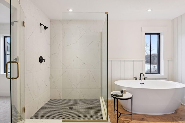 full bath with a marble finish shower, a soaking tub, a wainscoted wall, and recessed lighting