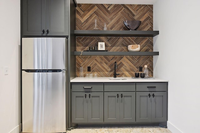 indoor wet bar featuring freestanding refrigerator, backsplash, and baseboards