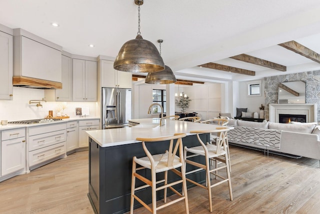 kitchen with appliances with stainless steel finishes, a sink, tasteful backsplash, light wood finished floors, and light countertops
