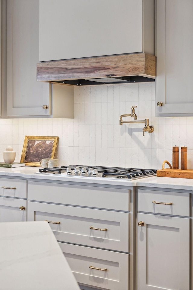 kitchen featuring light countertops, decorative backsplash, stainless steel gas stovetop, extractor fan, and gray cabinetry