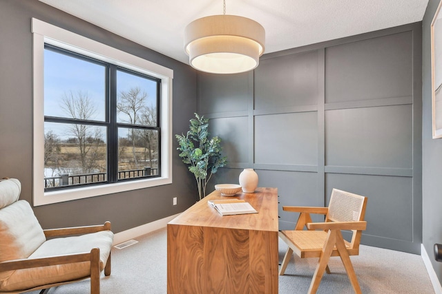 office space with carpet, baseboards, and a decorative wall