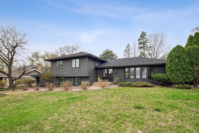 split level home featuring brick siding, a chimney, and a front yard