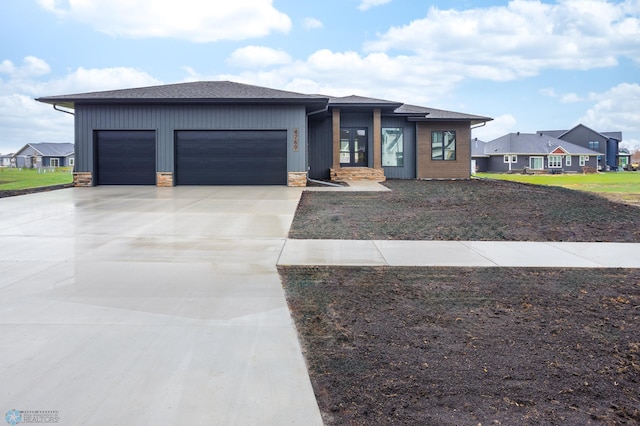 prairie-style house featuring a garage, roof with shingles, a residential view, and concrete driveway