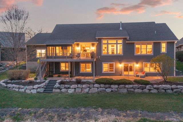 back of property with a lawn, roof with shingles, a wooden deck, and stairway