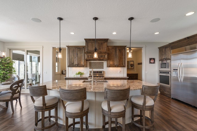 kitchen featuring a sink, decorative backsplash, dark wood-style flooring, and built in appliances