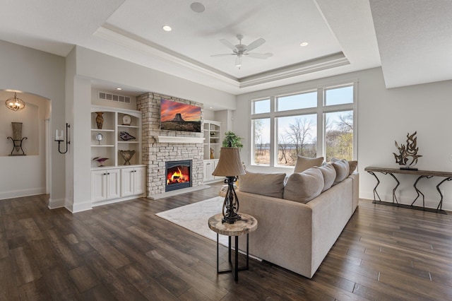 living room featuring visible vents, ceiling fan, a tray ceiling, and a large fireplace