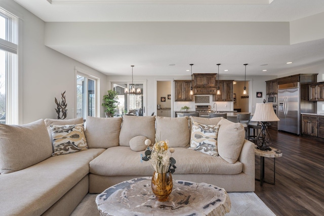living area featuring recessed lighting, dark wood-style flooring, a notable chandelier, and a healthy amount of sunlight