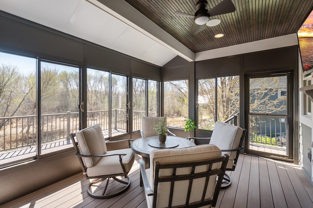 sunroom / solarium with a ceiling fan and beam ceiling
