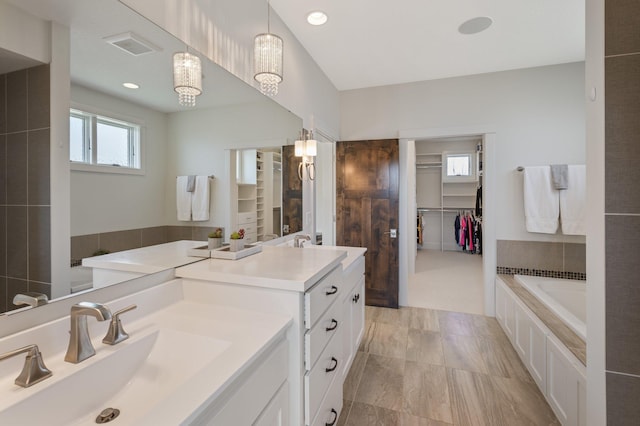 bathroom featuring a tub, a spacious closet, recessed lighting, and vanity