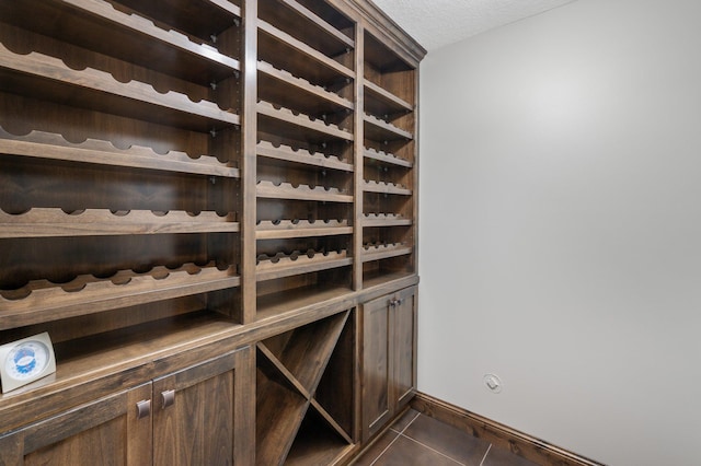 wine area with dark tile patterned flooring, a textured ceiling, and baseboards