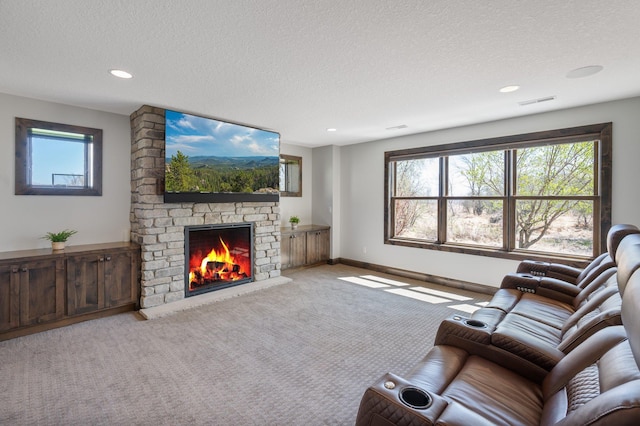 carpeted living area featuring a fireplace, a textured ceiling, recessed lighting, baseboards, and visible vents
