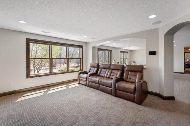carpeted living room with recessed lighting, arched walkways, a textured ceiling, and baseboards