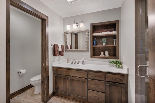 full bath with vanity, wood finished floors, toilet, a textured ceiling, and a stall shower