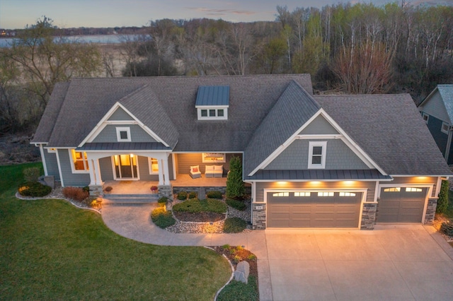 craftsman-style house featuring an attached garage, stone siding, a front yard, covered porch, and driveway