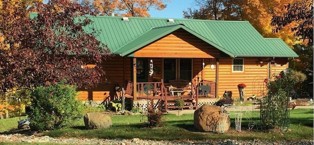 back of property with log veneer siding and metal roof