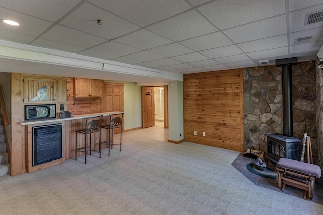 2064 View Dr NW, Walker, MN 56484 - living room featuring a wood stove, a bar, light colored carpet, a drop ceiling, and wooden walls