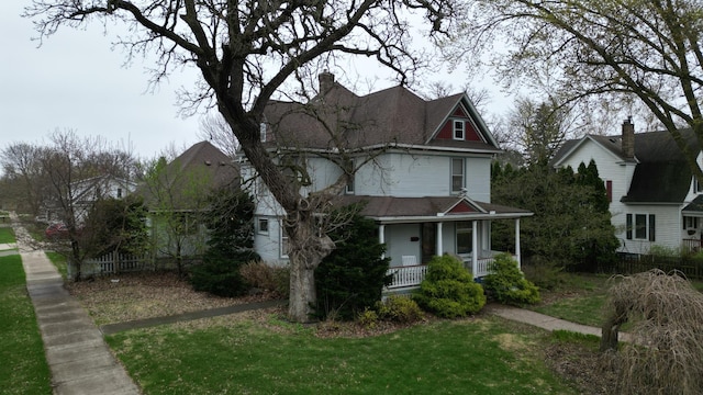 victorian home featuring fence, a porch, and a front yard