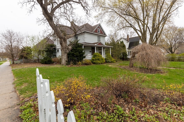 view of home's exterior featuring a porch, fence, and a yard