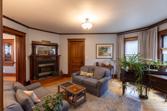 living room with a high end fireplace, baseboards, ornamental molding, and light wood-style flooring