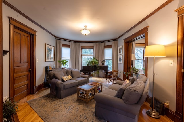 living room featuring plenty of natural light, ornamental molding, baseboards, and wood finished floors