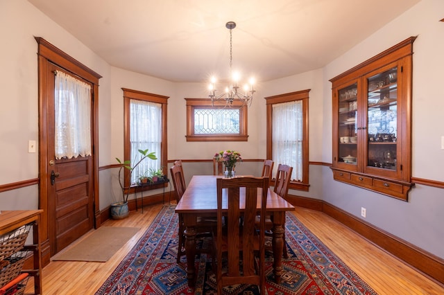 dining room featuring baseboards, a notable chandelier, and light wood finished floors