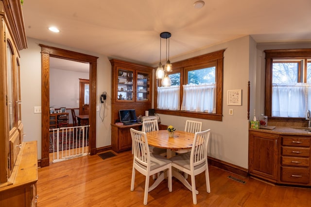 dining room with baseboards, plenty of natural light, and light wood-style flooring