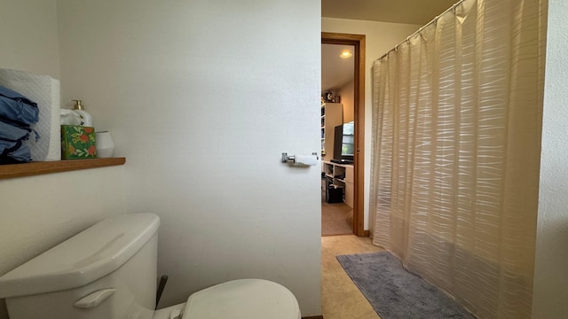 bathroom featuring toilet and curtained shower