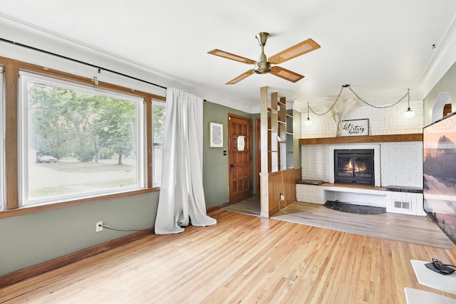6001 Bryant Ave N, Brooklyn Center, MN 55430 - unfurnished living room with wood finished floors, a brick fireplace, a ceiling fan, and baseboards