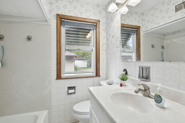 6001 Bryant Ave N, Brooklyn Center, MN 55430 - bathroom featuring wallpapered walls, tile walls, toilet, vanity, and tub / shower combination