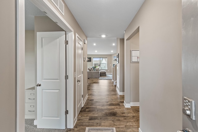 hall with visible vents, recessed lighting, baseboards, and dark wood-type flooring