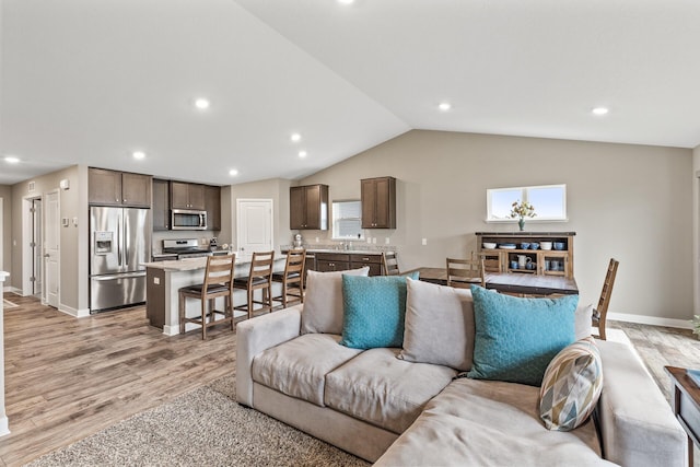 living room featuring light wood-style floors, recessed lighting, baseboards, and lofted ceiling