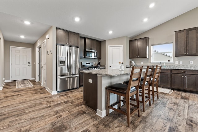 kitchen featuring a center island, appliances with stainless steel finishes, wood finished floors, and dark brown cabinets