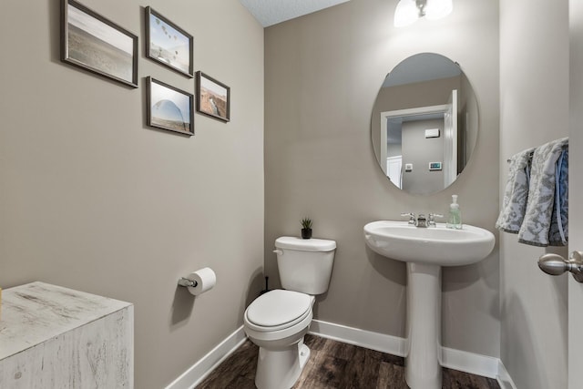 bathroom featuring baseboards, a sink, wood finished floors, and toilet