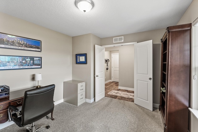 carpeted home office with a textured ceiling, baseboards, and visible vents
