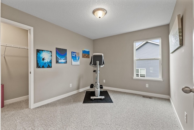 workout room featuring carpet floors, a textured ceiling, baseboards, and visible vents