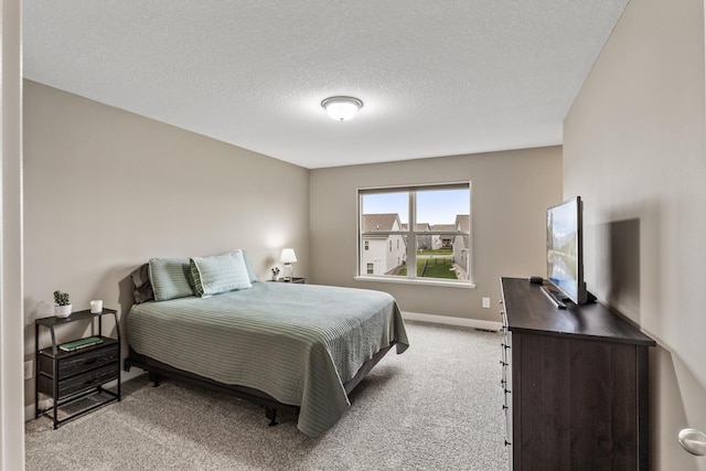 bedroom featuring baseboards, a textured ceiling, and light carpet