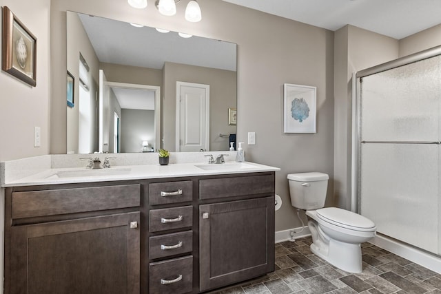 bathroom with double vanity, a sink, a stall shower, and toilet