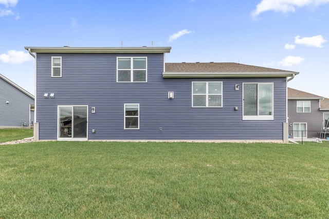 back of property featuring a shingled roof and a yard