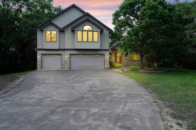 7884 341st St, Lent Twp, MN 55079 - view of front of home featuring asphalt driveway, a garage, stone siding, and a front lawn