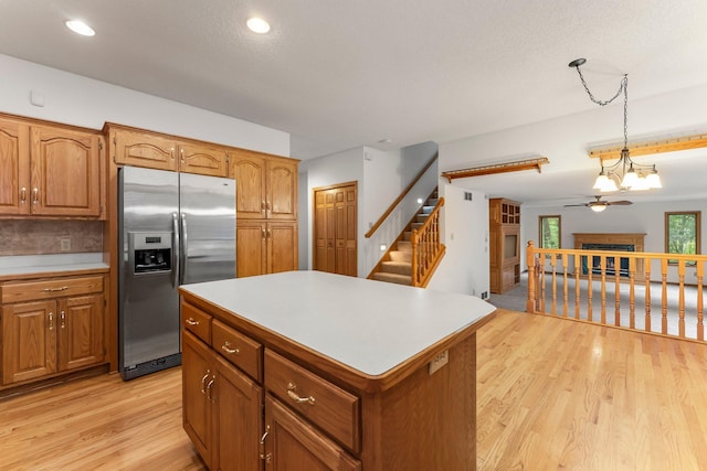 7884 341st St, Lent Twp, MN 55079 - kitchen with stainless steel fridge, a fireplace, light wood-style floors, brown cabinetry, and recessed lighting