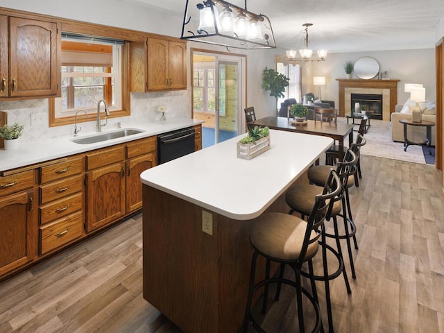 kitchen featuring black dishwasher, a sink, a kitchen breakfast bar, a center island, and decorative backsplash