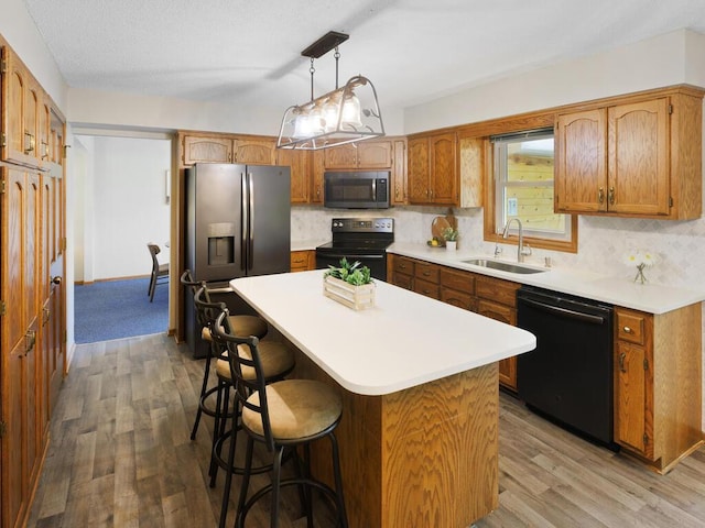 kitchen featuring black appliances, a sink, wood finished floors, and decorative backsplash