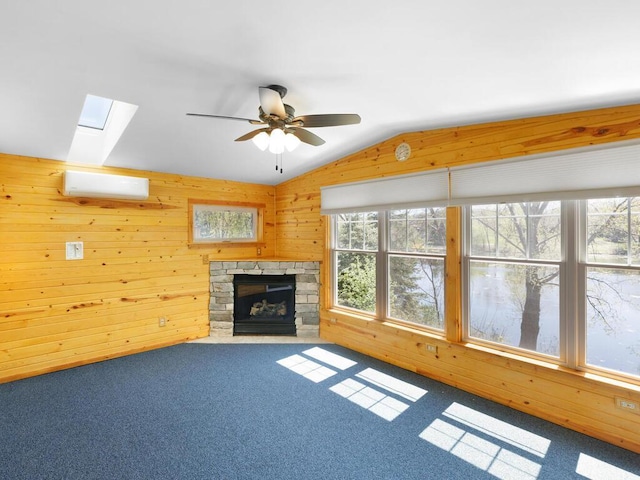 unfurnished living room with a skylight, wooden walls, lofted ceiling, a wall mounted AC, and carpet
