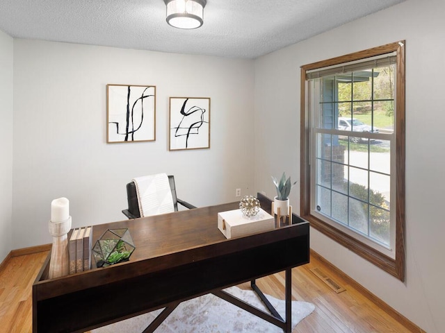 office with light wood finished floors, baseboards, and a textured ceiling