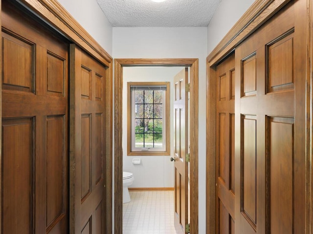 bathroom featuring toilet, baseboards, a textured ceiling, and tile patterned floors