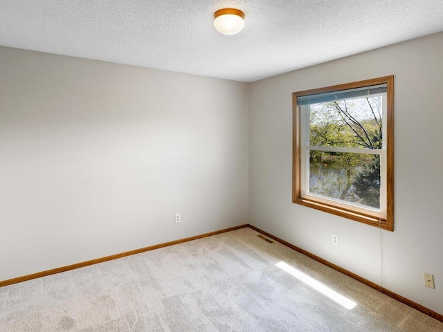 carpeted spare room featuring baseboards and a textured ceiling